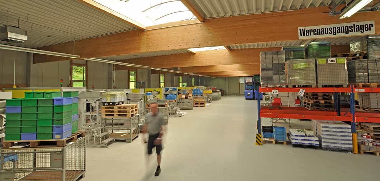 Warenausgangslager in der Produktionshalle des Metallwaren-Herstellers mit Regalen, Paletten und Mitarbeiter