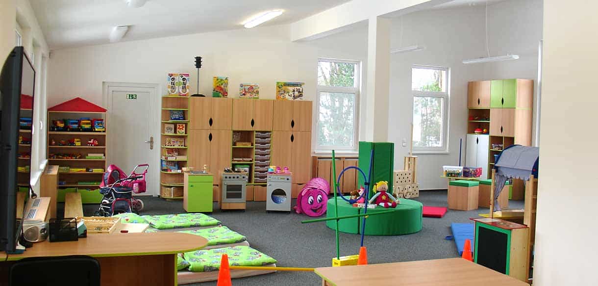 Gruppenraum des Kindergartens Äpfelchen mit Holzregalen, Spielküche und Spielzeug