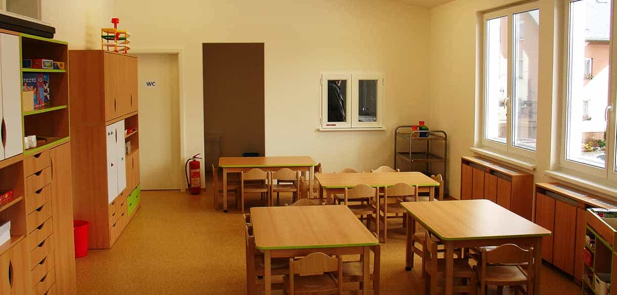 Gruppenraum des Kindergartens Äpfelchen mit Holztischen, Kinderstühlen und Schränken