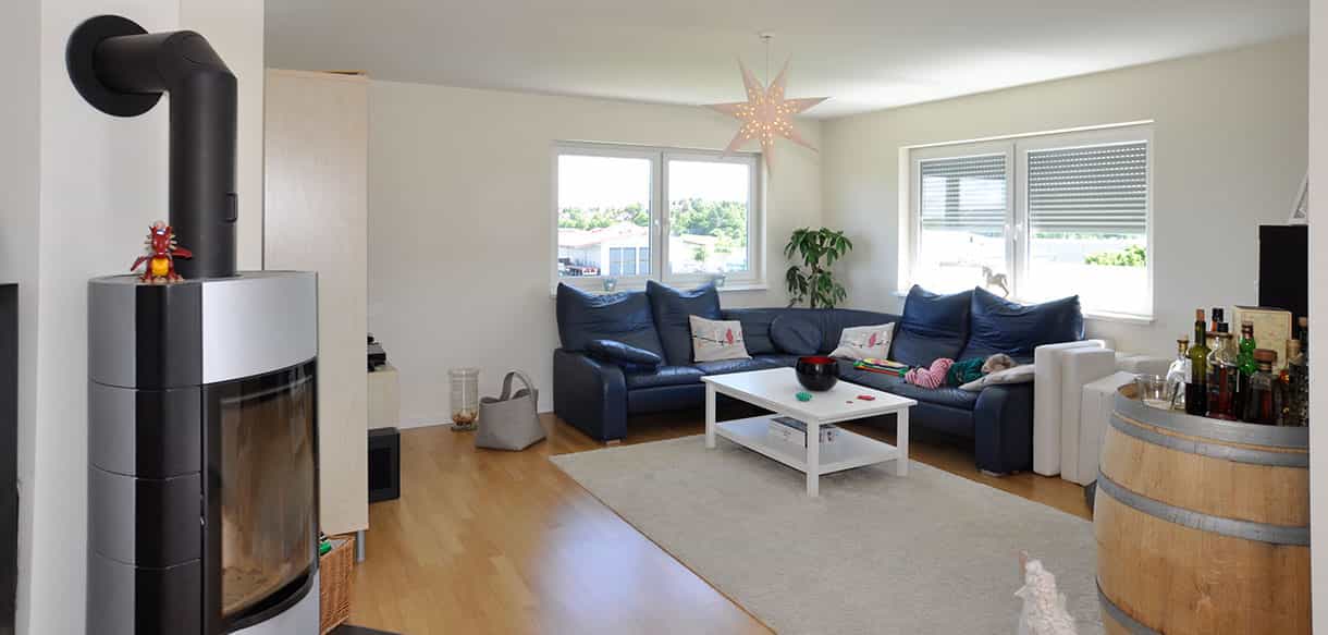 Wohnzimmer mit blauem Sofa, Kaminofen und Holzboden in der Wohnung über der Arcus Physiotherapiepraxis