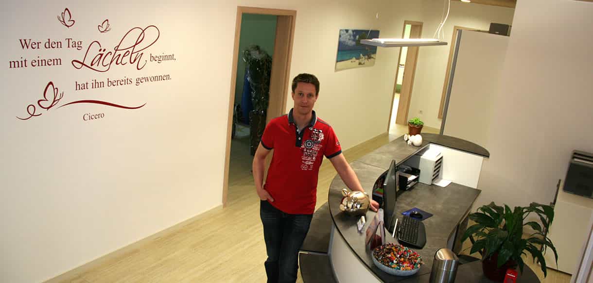 Empfang der Physiotherapiepraxis Zielke mit Mitarbeiter an der Theke und Wandtattoo