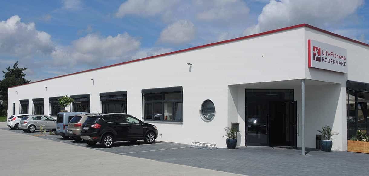 Längsseite des Fitnessstudios Life Fitness Rödermark mit Parkplatz und rundem Fenster