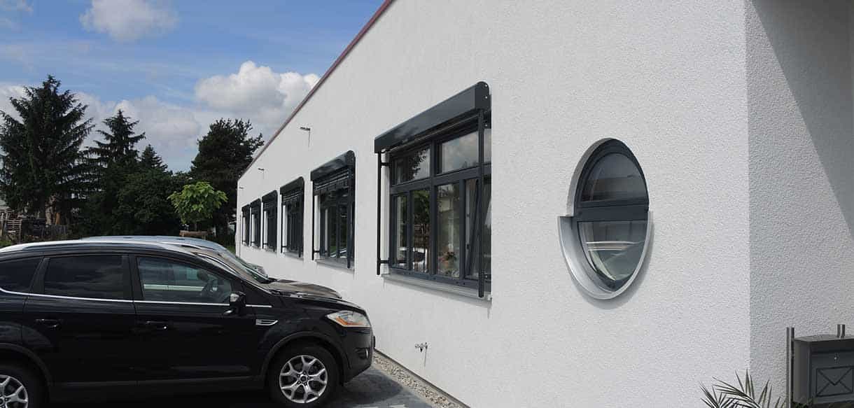 Fassadendetail von Life Fitness Rödermark mit rundem Fenster und parkendem Auto