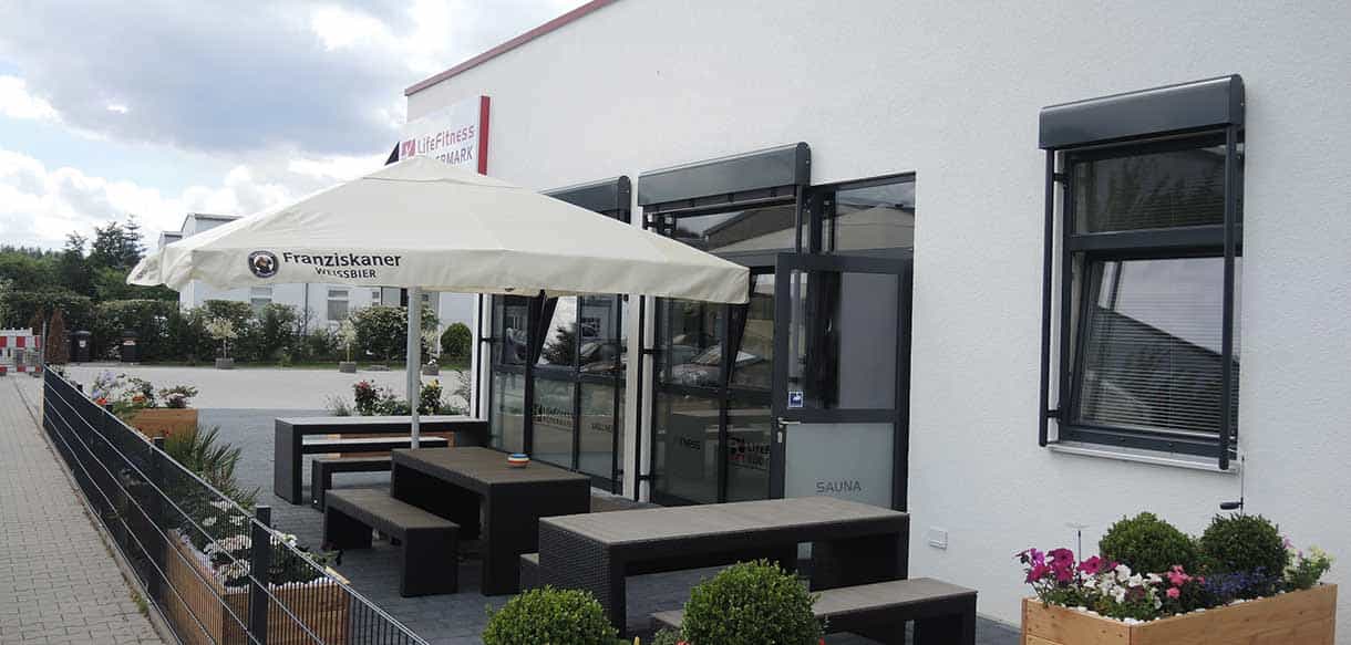 Terrasse mit Sonnenschirm und Sitzgruppe am Fitnessstudio Life Fitness Rödermark
