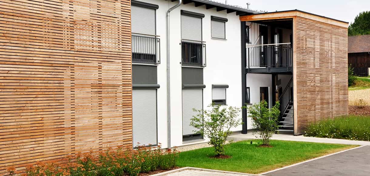 Fassade des Arbeiterwohnheims Ammer mit Lärchenholz-Lamellen am Treppenhaus und kleinen Balkonen