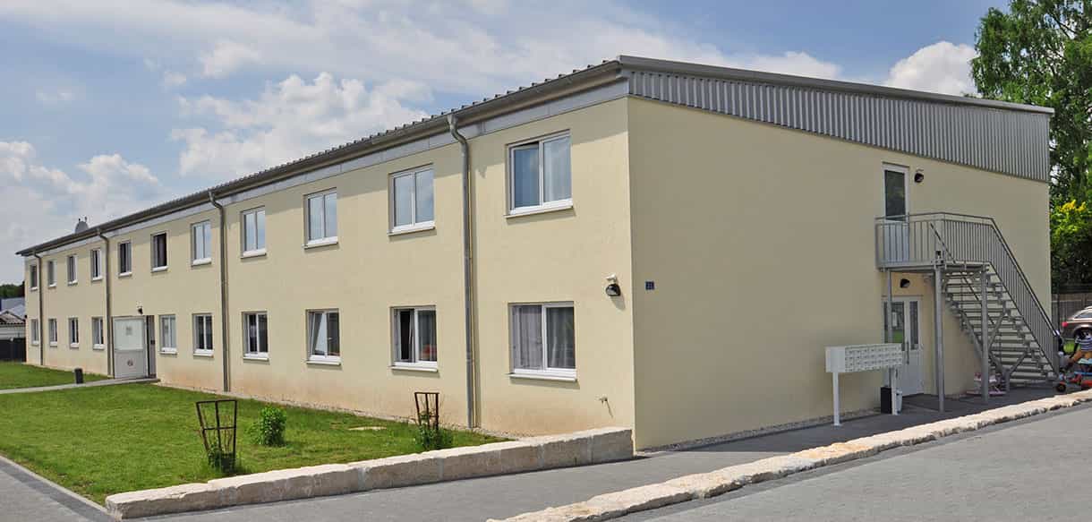 Asylbewerberheim in Neunkirchen am Sand mit gelber Fassade und Außentreppe von Haas Gewerbebau