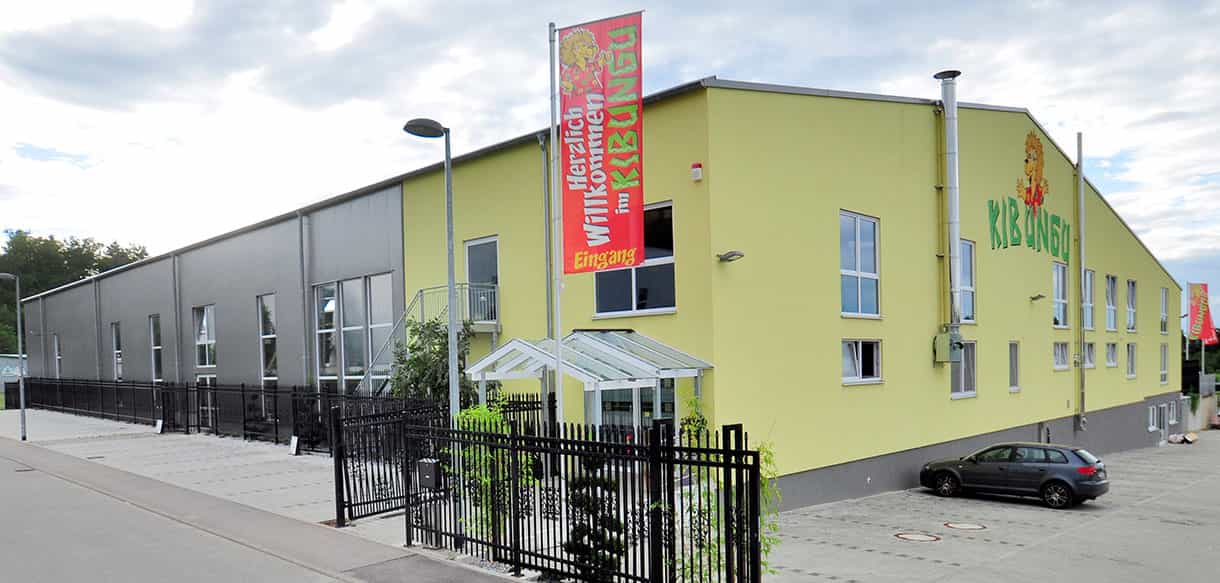 Außenansicht des Kibungu Indoor-Spielparadieses in Wurmberg mit gelb-grauer Fassade und Fahne