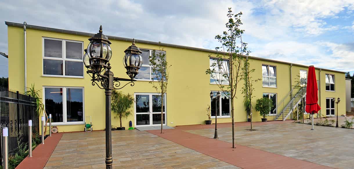 Terrasse mit Laternen und roten Sonnenschirmen vor dem Kibungu Indoor-Spielparadies in Wurmberg