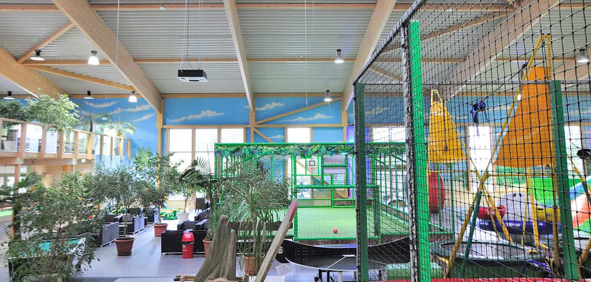Spielhalle des Kibungu Indoor-Spielparadieses mit Klettergerüst unter der Holzdachkonstruktion