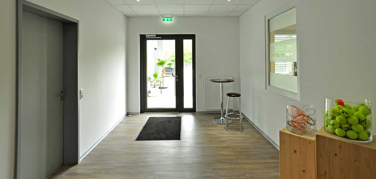 Eingangsbereich mit Glastür und Stehtisch im Bürogebäude von BC Sports in Deggingen