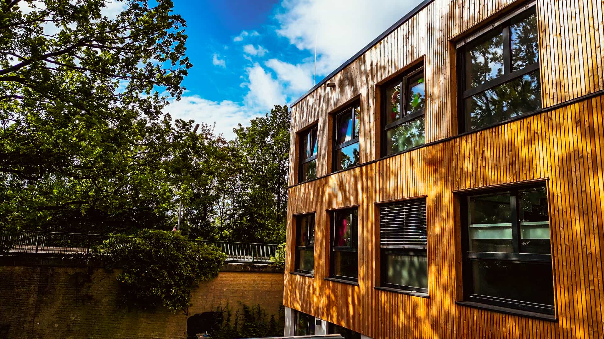 Dreigeschossige Holzfassade der Kita in Hamburg von Haas Gewerbebau zwischen Bäumen