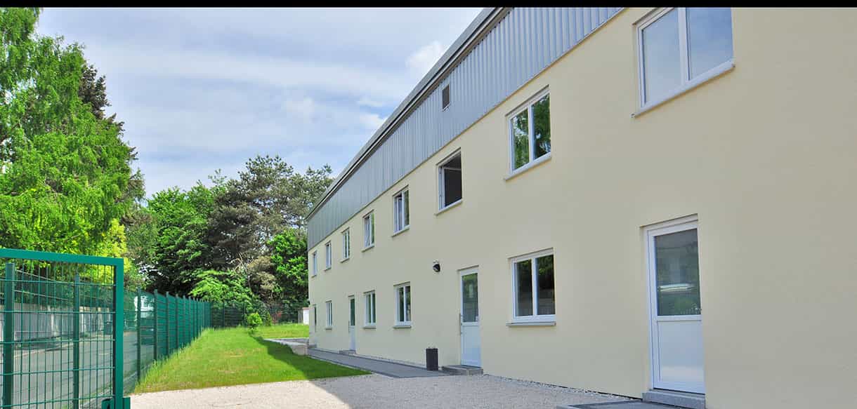 Zweigeschossiges Wohnheim von Haas Wohnbau mit heller Putzfassade, Referenz für Unterkünfte für Saisonarbeiter