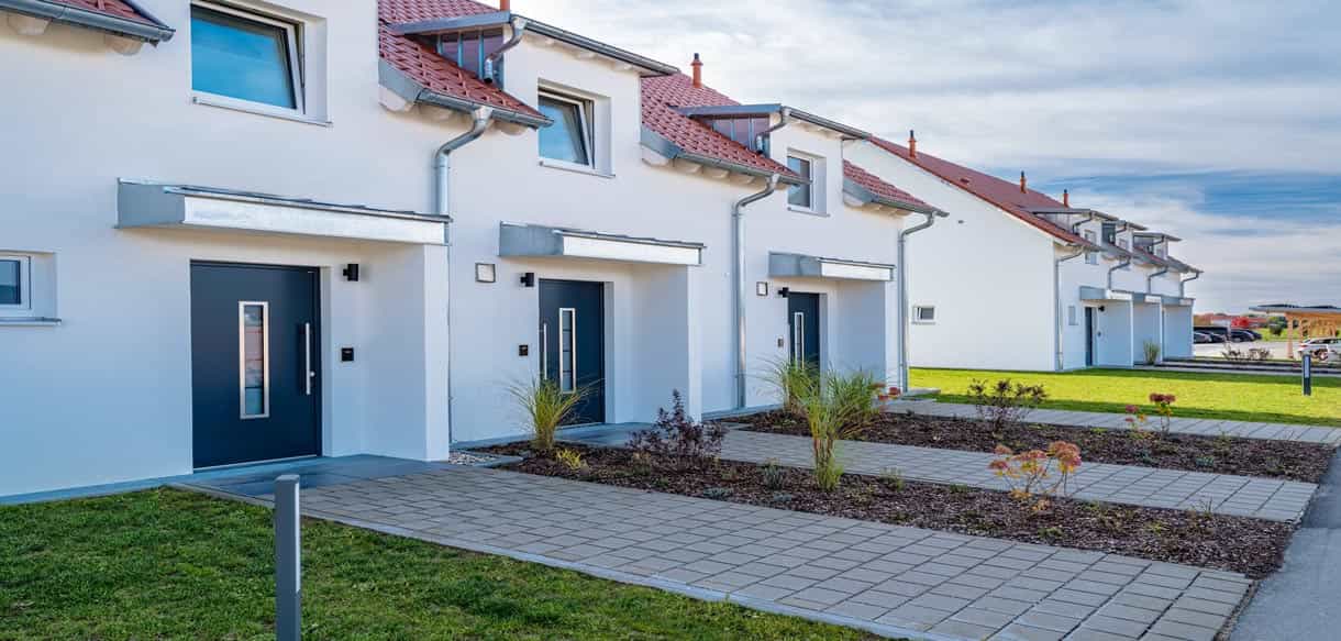 Eingangsbereiche der Ferienhäuser mit dunklen Haustüren und gepflastertem Weg im Bachhof Resort Kirchroth