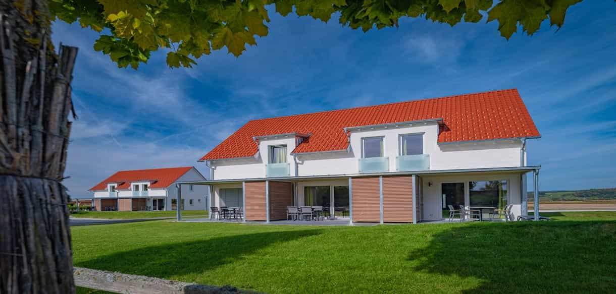 Ferienhäuser mit Terrassen und Balkon hinter der Rasenfläche im Bachhof Resort bei Straubing