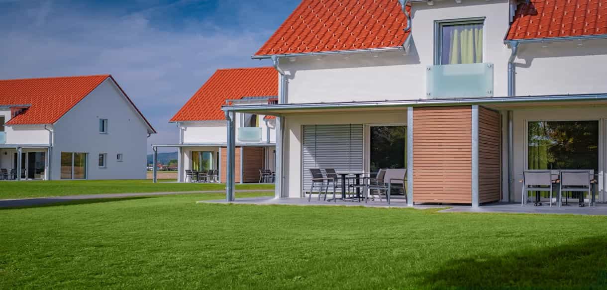 Terrasse mit Holzlamellen-Sichtschutz und Gartenmöbeln an einem Ferienhaus im Bachhof Resort Kirchroth