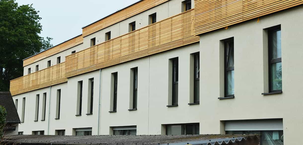 Dreigeschossige Wohnhausanlage Mistelbach mit weißer Fassade und holzverkleidetem Obergeschoss