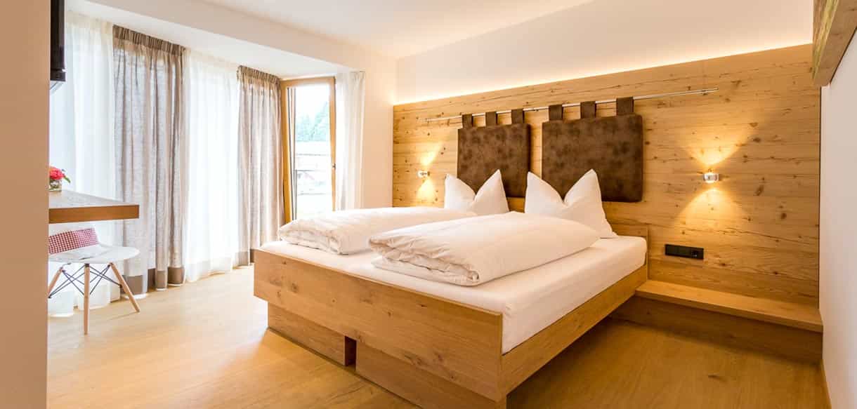 Gästezimmer mit Doppelbett und Holzwand im modernen ländlichen Stil in der Pension Moarhof