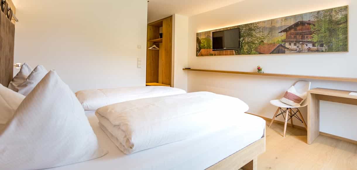 Gästezimmer mit Doppelbett, Schreibtisch und Wandbild in der Pension Moarhof von Haas Fertigbau