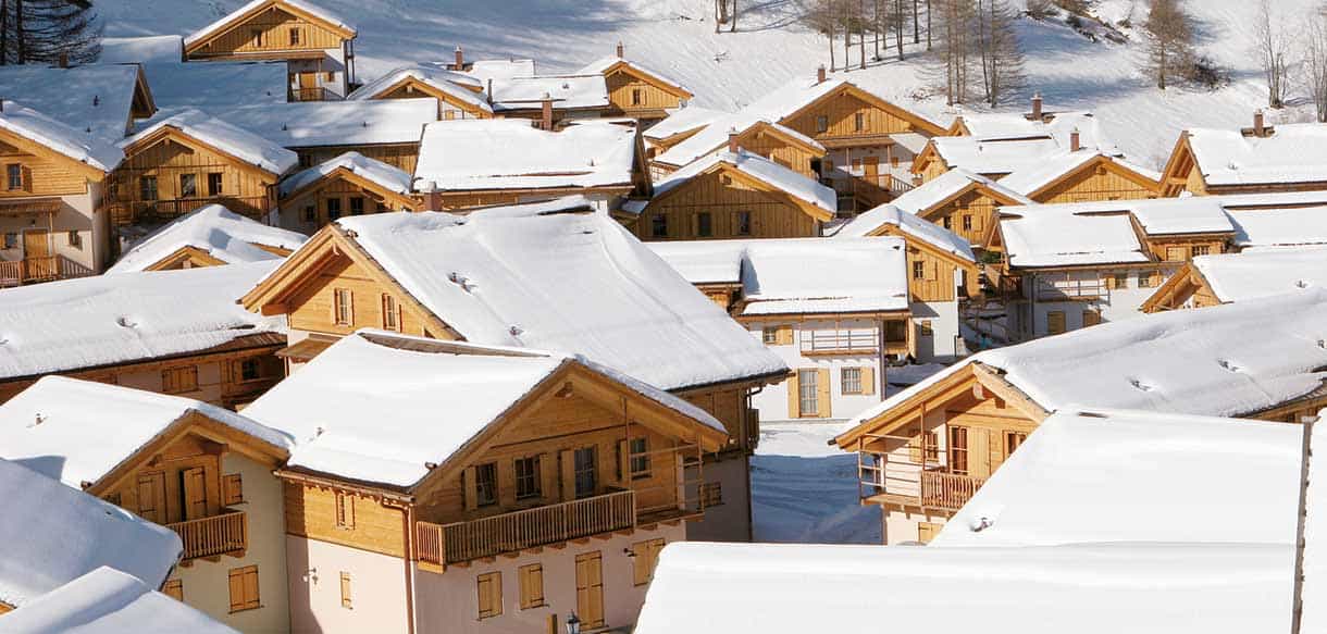 Blick über die verschneiten Chalet-Dächer der Ferienwohnanlage mit 205 Wohneinheiten in Pragelato
