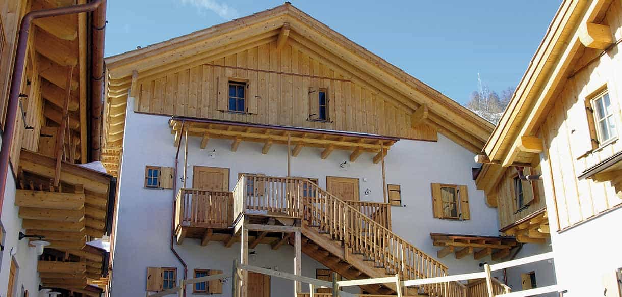 Chalet-Fassade mit Holzaußentreppe und Fensterläden in der Ferienwohnanlage Pragelato