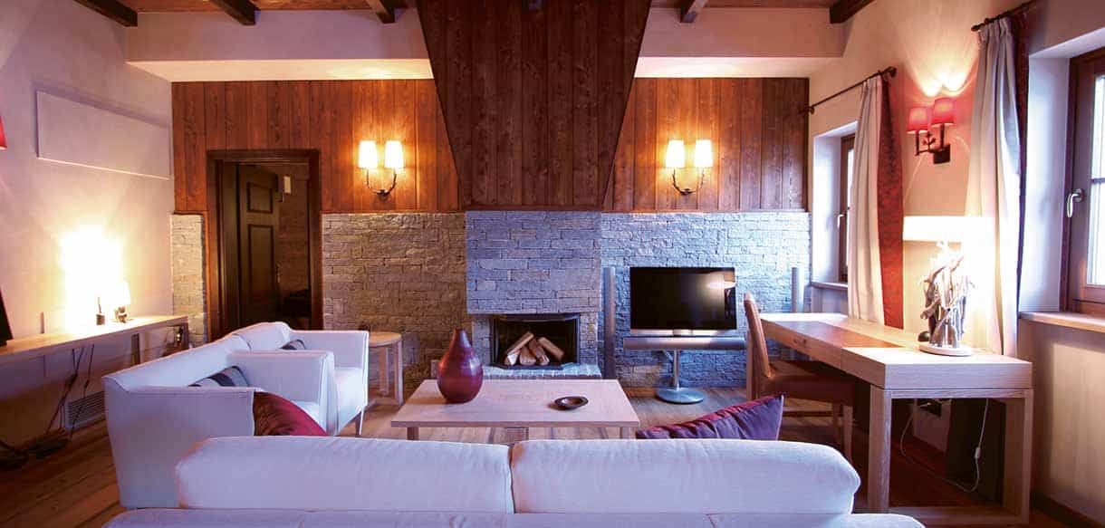 Wohnzimmer mit Kamin, hellen Sofas und Fernseher in einem Chalet-Appartement in Pragelato