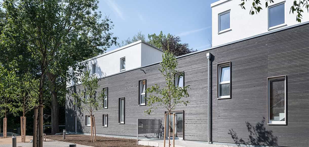 Außenansicht eines der vier Wohnhäuser mit anthrazitfarbener Holzfassade im Donau-Wohnpark