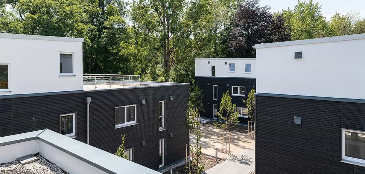 Blick von der Dachterrasse über die Wohnhäuser mit dunkler Holzfassade im Donau-Wohnpark