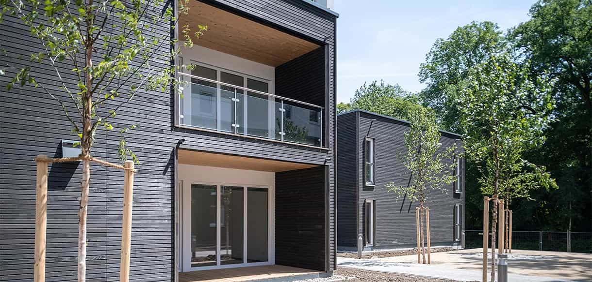 Loggien mit Holzuntersicht und Glasgeländer an der dunklen Holzfassade eines Wohnhauses im Donau-Wohnpark