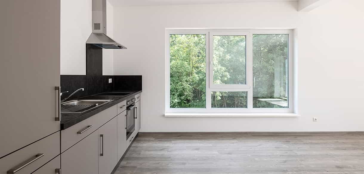 Küche mit weißen Fronten, dunkler Arbeitsplatte und Fenster in einer Wohnung des Donau-Wohnparks