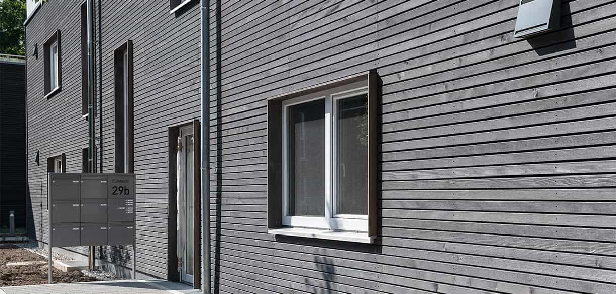 Detail der grauen Holzschalung mit Fenstern an einem Wohnhaus des Donau-Wohnparks