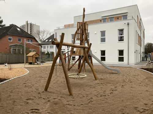 Dreigeschossige Kita KD3 von Haas Gewerbebau mit Staffelgeschoss und Holzkletterpyramide mit Rutsche
