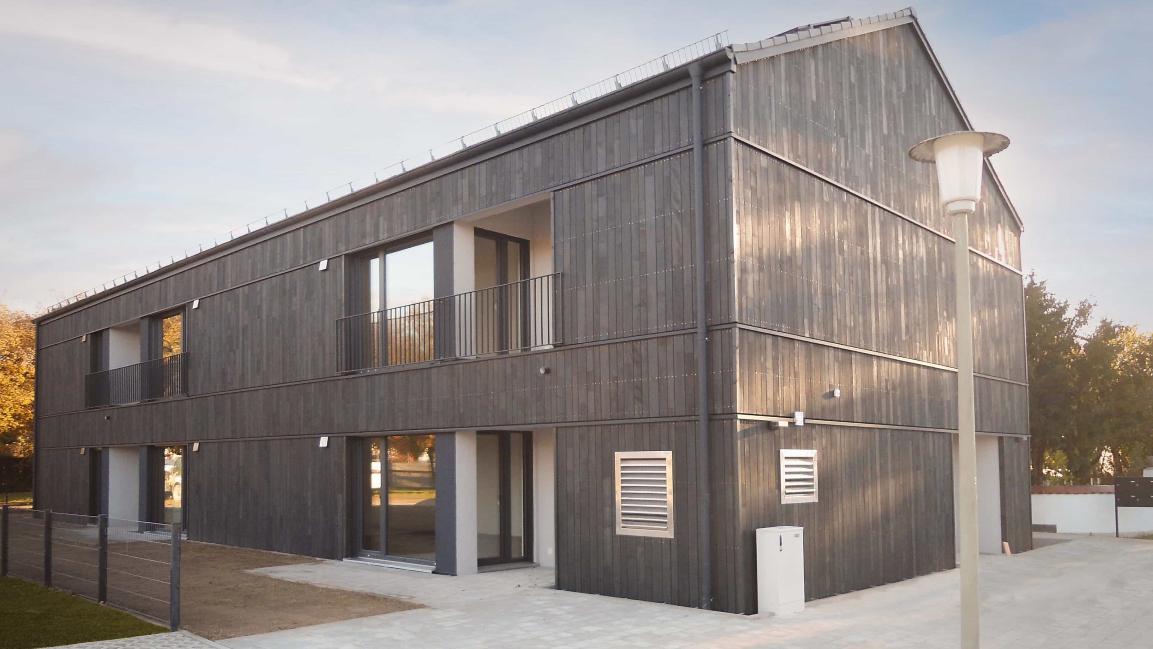 Mehrfamilienhaus von Haas Wohnbau mit vergrauter Holzfassade und Balkonen, Teaser zum Wohnbau-Katalog