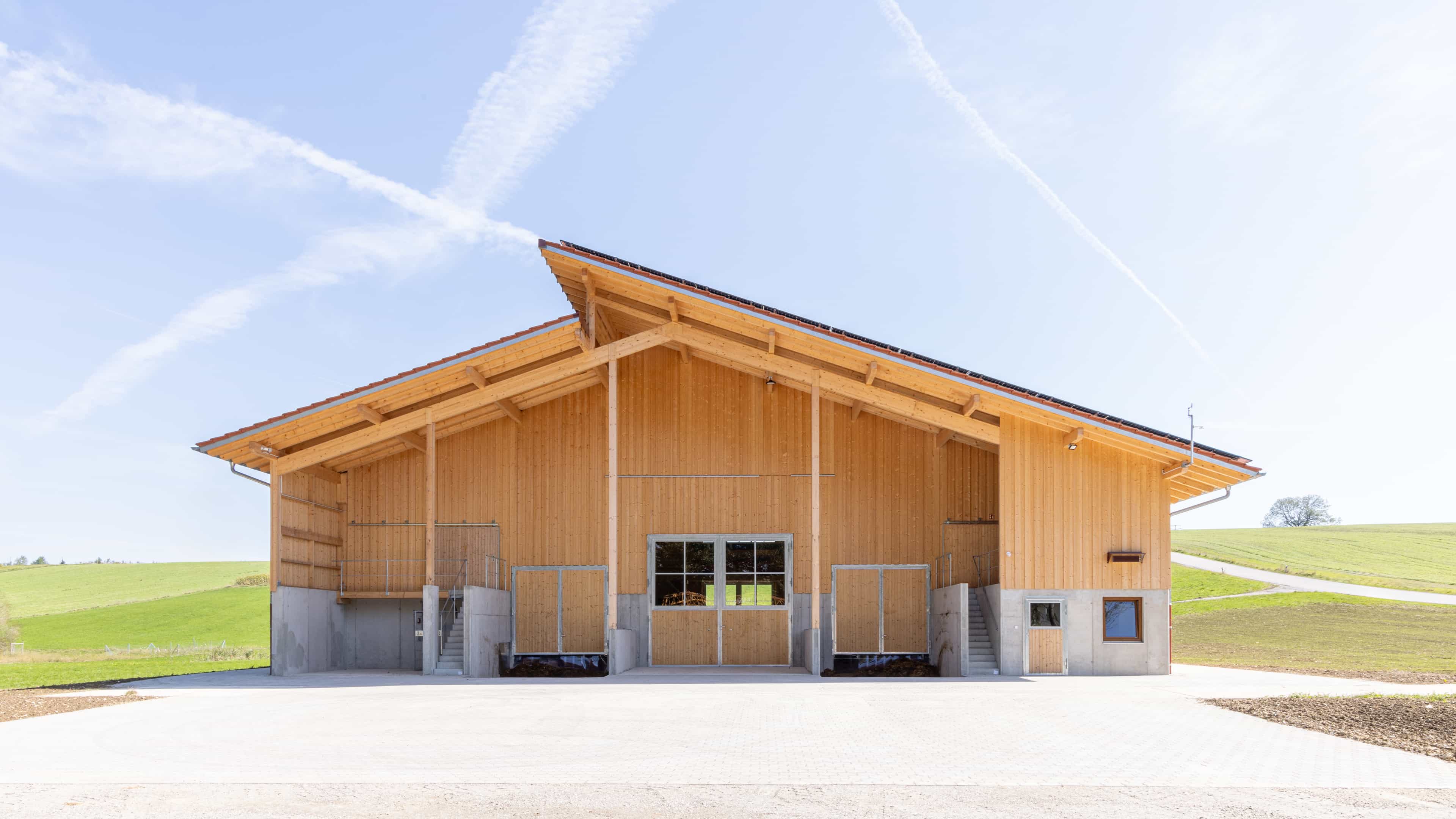 Giebelseite des Rinderstalls mit Holzfassade und weit auskragendem Dach