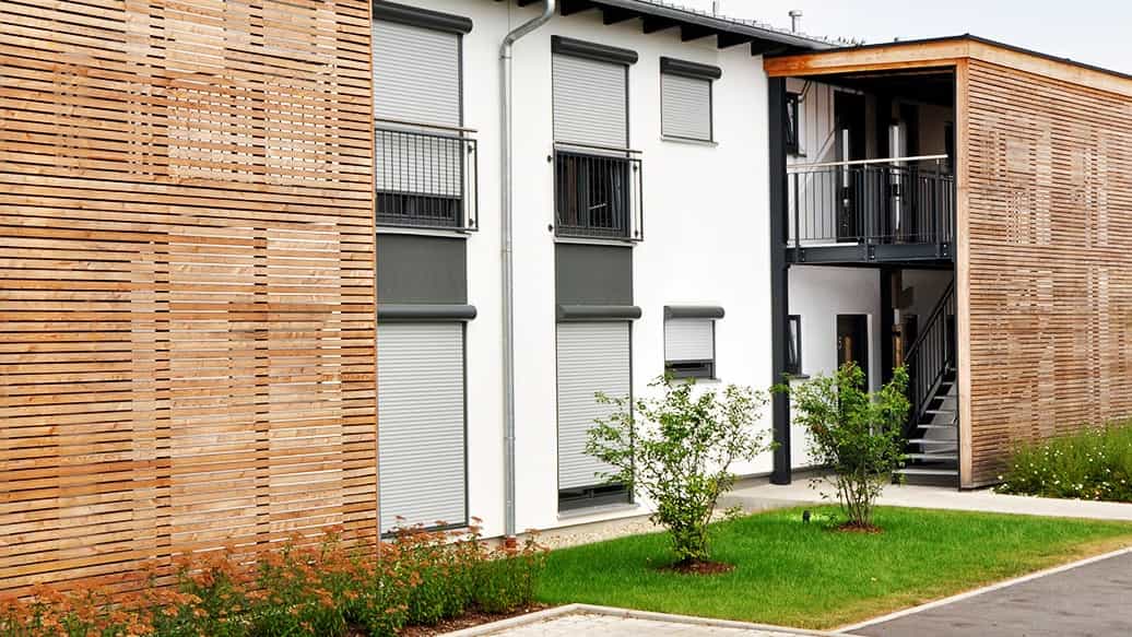 Fassade mit vertikalen Holzlamellen und weißem Putz an einem Mehrfamilienhaus von Haas Wohnbau