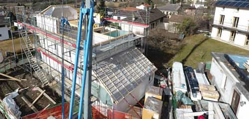 Luftaufnahme der Baustelle in Riva, Schweiz, mit Kran und Holzelementen, Haas Holzbausysteme