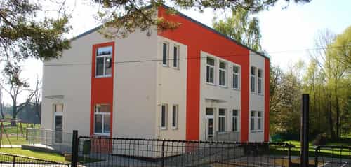 Zweigeschossiger Kindergarten Äpfelchen in Velké Přílepy mit weiß-oranger Fassade und Zaun