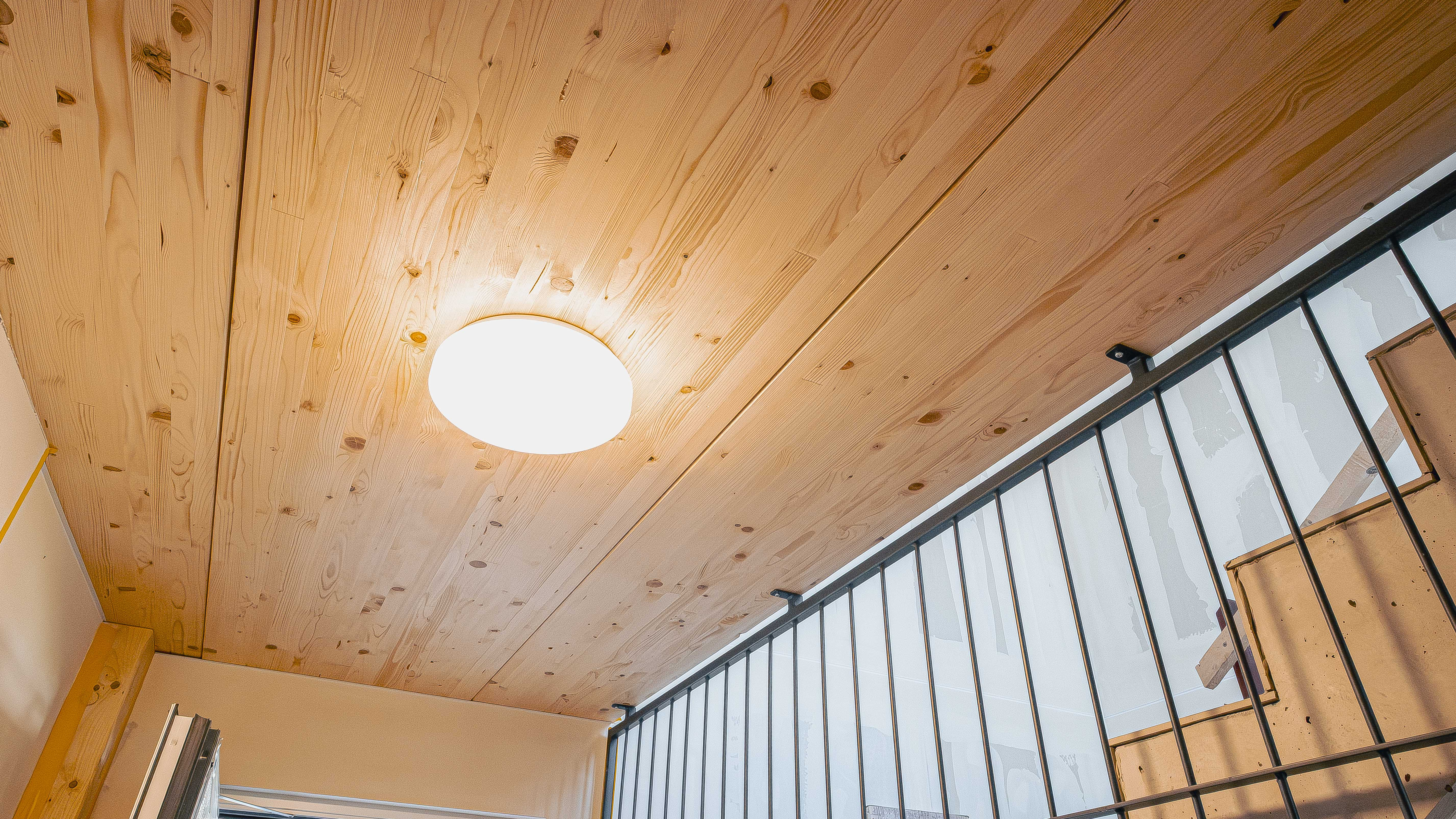 Treppenhaus mit Holzdecke, Deckenleuchte und Metallgeländer in der Wohnanlage mit 15 Wohneinheiten in Eching