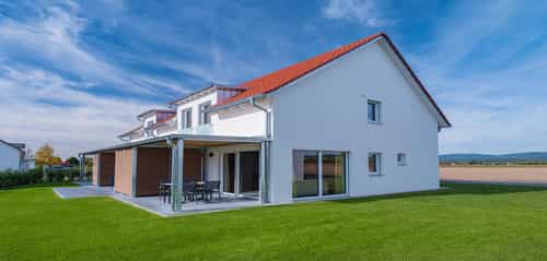 Ferienhaus mit überdachter Terrasse, Holzelementen und rotem Ziegeldach im Bachhof Resort Kirchroth