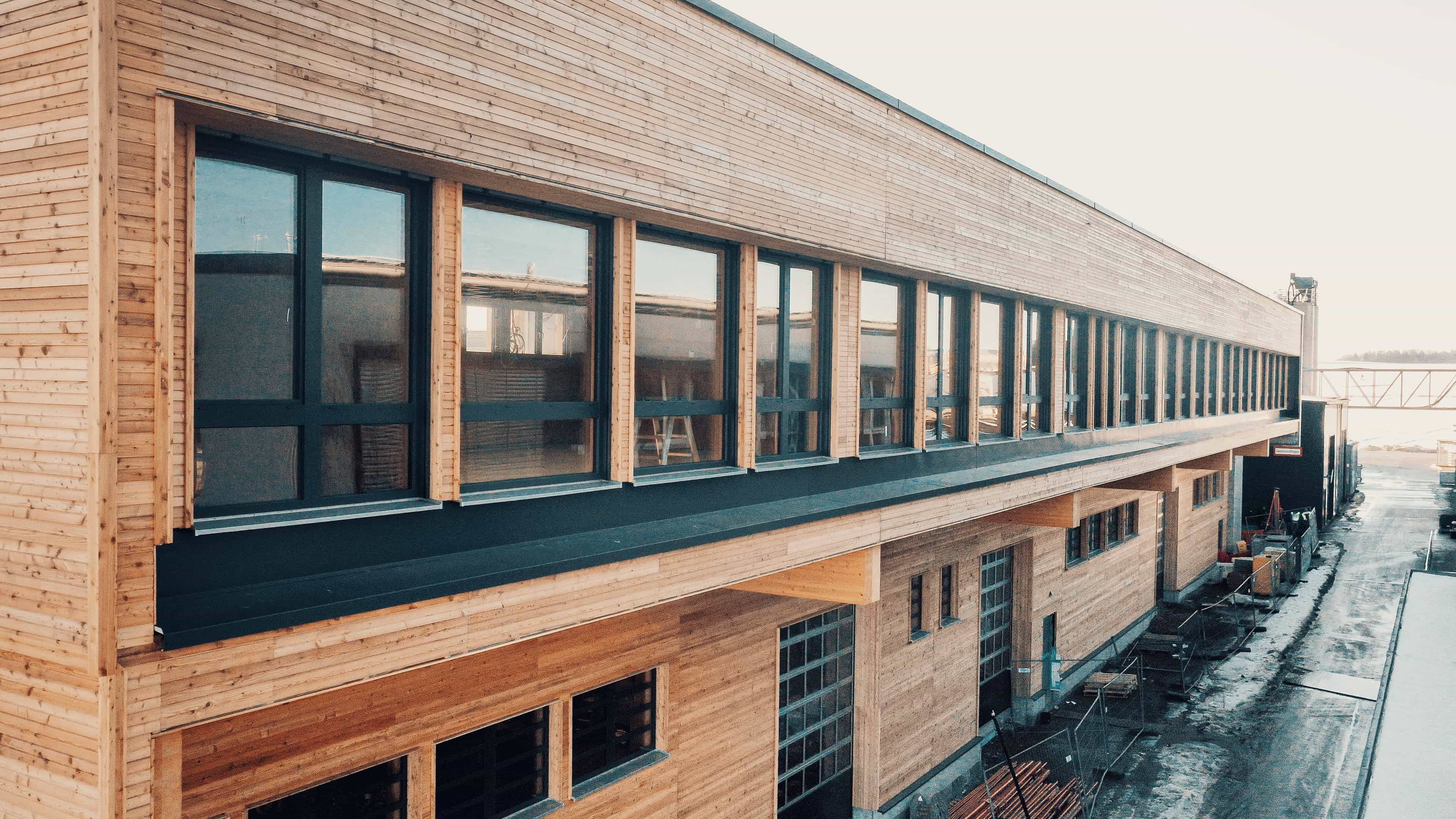 Langgestreckter Neubau mit horizontaler Holzfassade und Fensterband auf der Baustelle Wallstabe von Haas Fertigbau