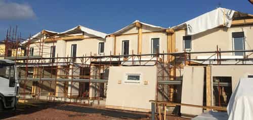 Baustelle der Doppelhäuser in Dinazzano mit Gerüst und Holzdachkonstruktion, Hausbausatz Haas Holzbausysteme