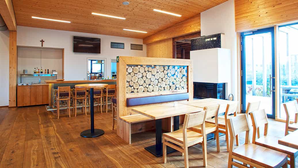 Gastraum mit Holzdecke, Tresen und Sitzbank in einer Haas Gewerbehalle, Referenzmotiv zur DACH+HOLZ 2024