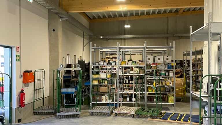 Lagerhalle mit Rollcontainern und Regalen unter einer Holzdecke, neues Betriebsgebäude der Ökokiste Donau-Wald