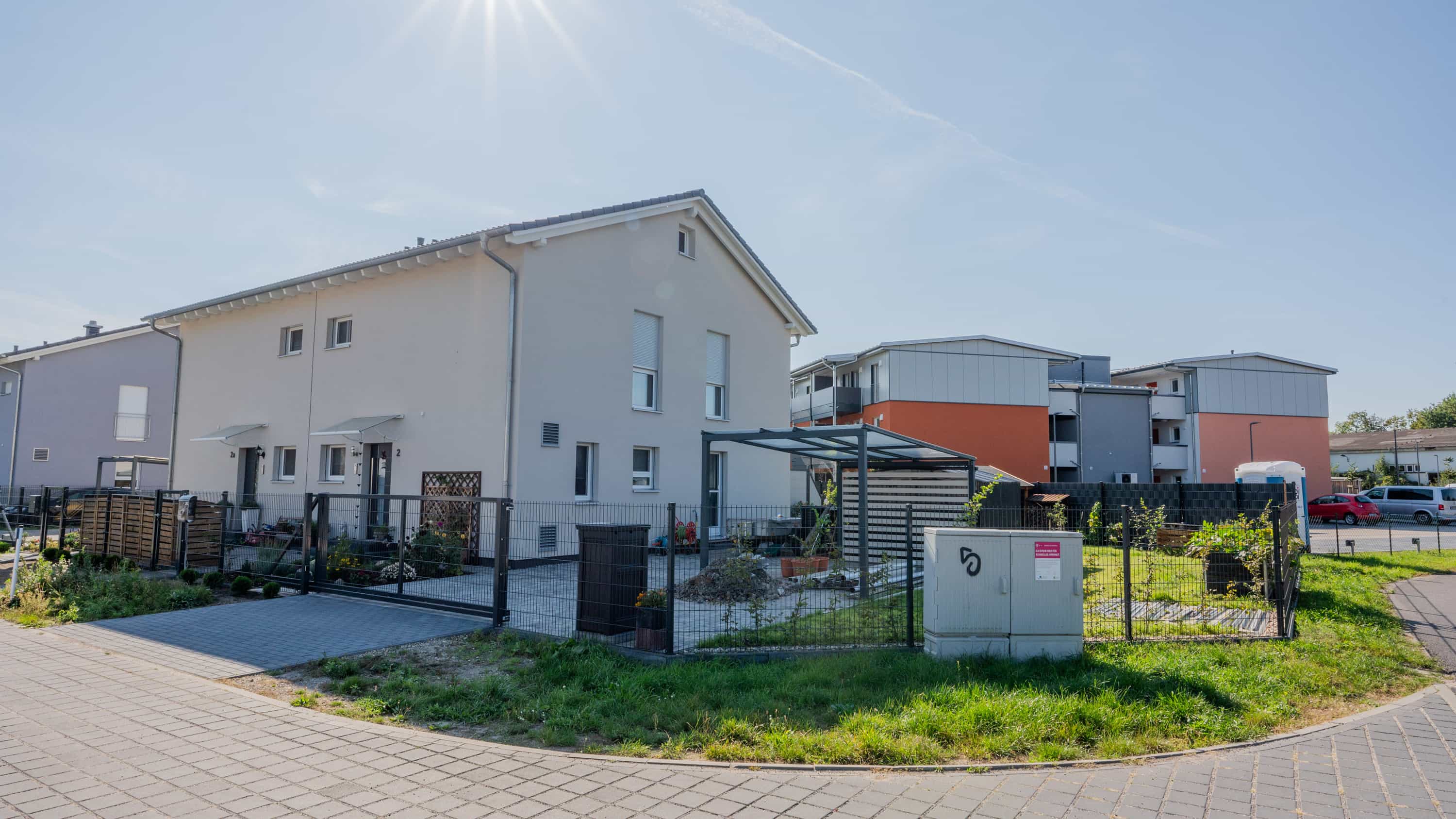 Einfamilienhaus mit Carport und Mehrfamilienhaus im Hintergrund im Wohnquartier Zum Glück Bötzow