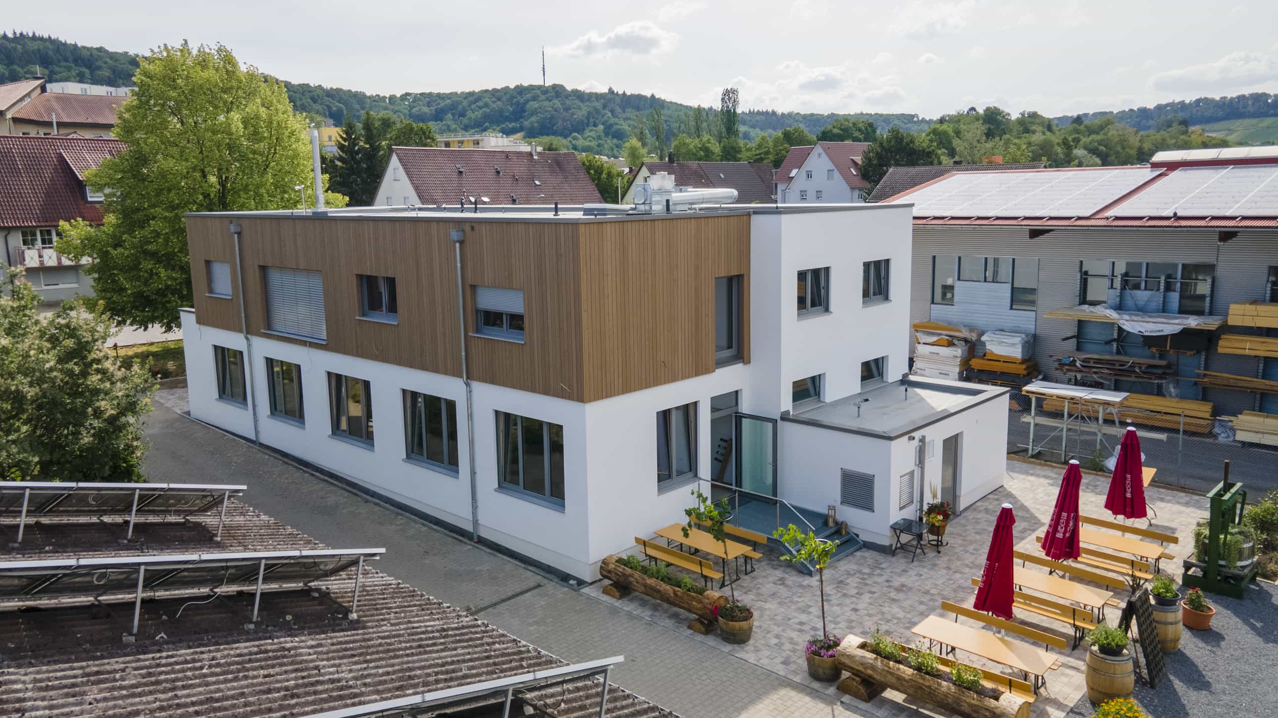 Luftaufnahme eines zweigeschossigen Gebäudes mit Holz- und Putzfassade und Terrasse, Objektbericht Haas Gewerbebau