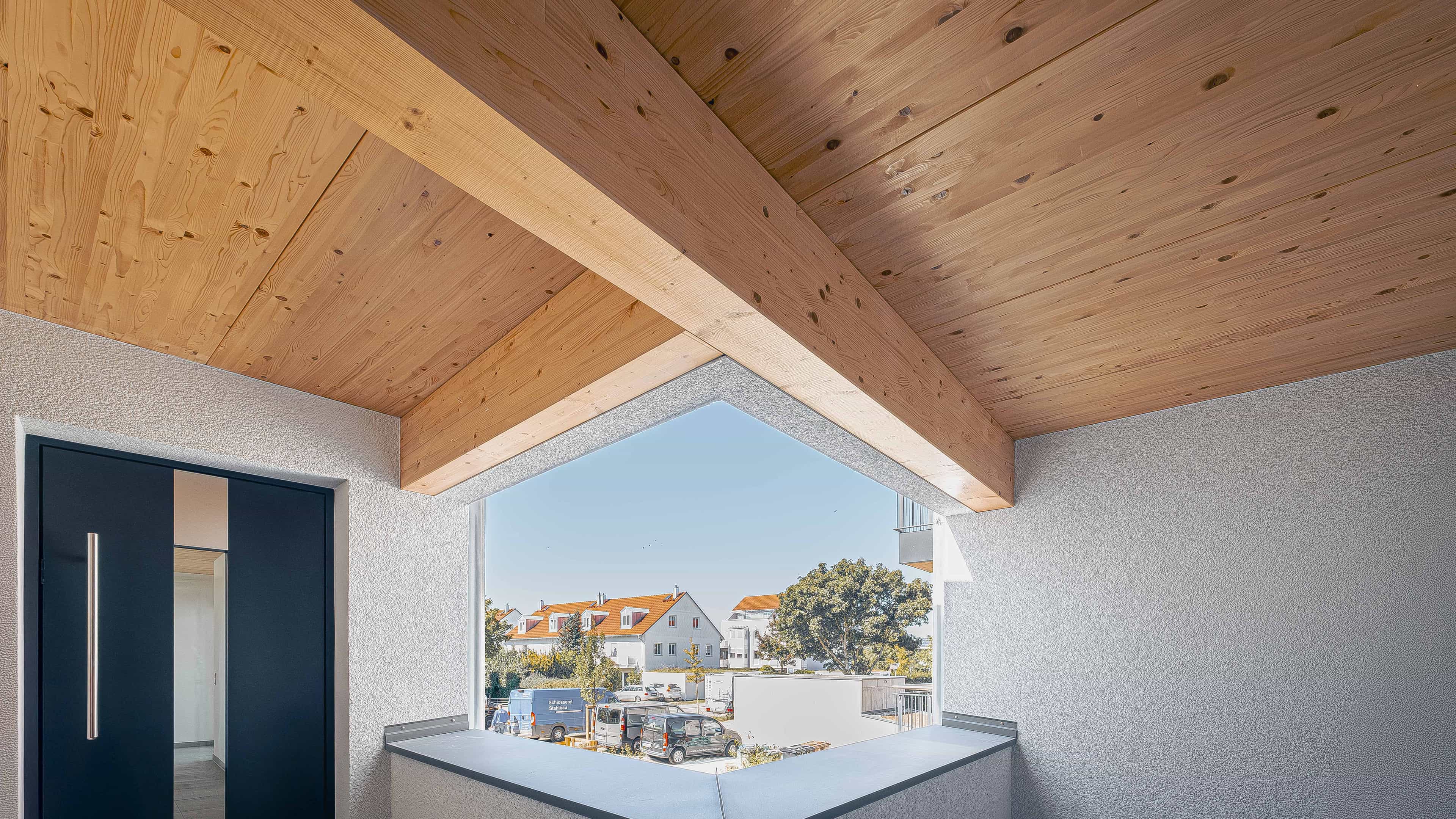 Überdachter Freisitz mit Holzdecke und Ausblick auf die Nachbarhäuser in der Wohnanlage Eching