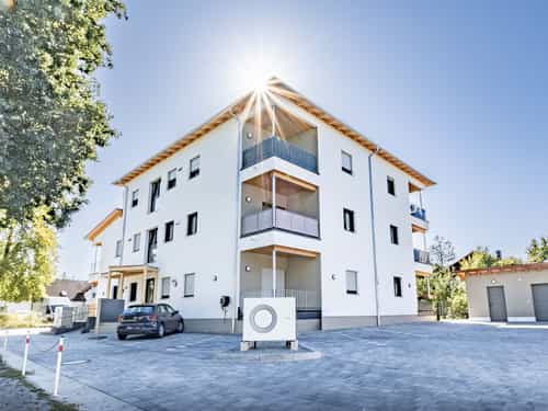 Dreigeschossige Wohnanlage mit 10 Wohneinheiten in Eichendorf mit Balkonen und Wärmepumpe im Gegenlicht