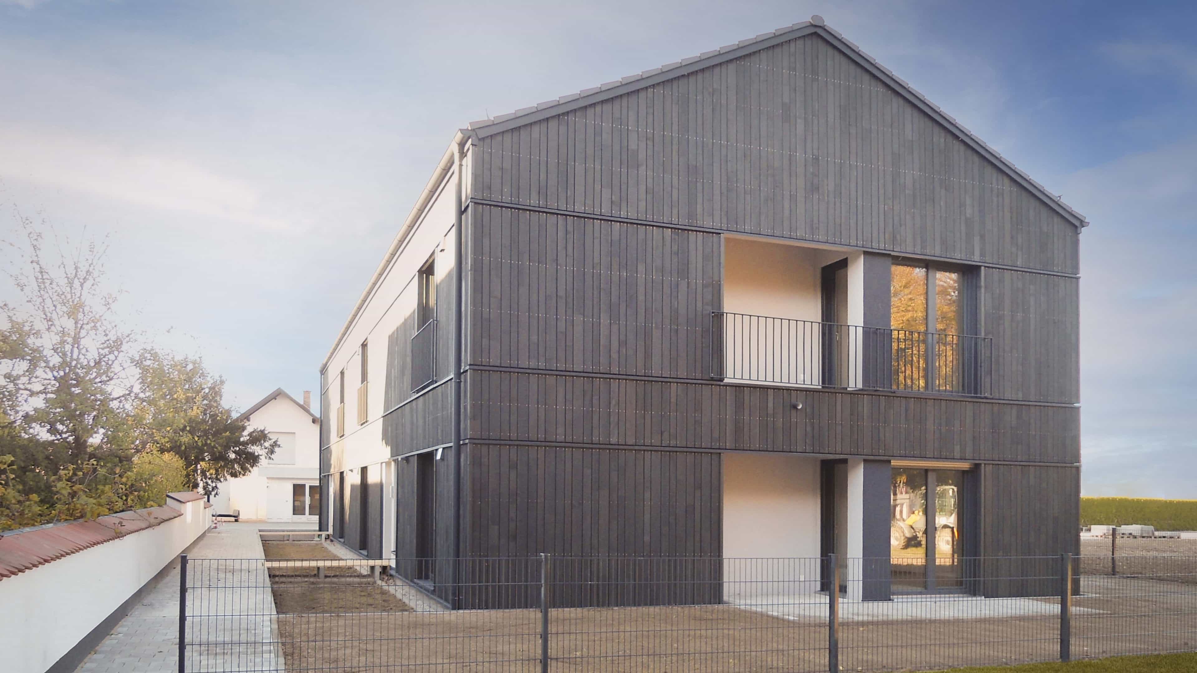 Wohnhaus mit Satteldach und grauer Holzfassade der Wohnanlage in Gern von Haas Fertigbau