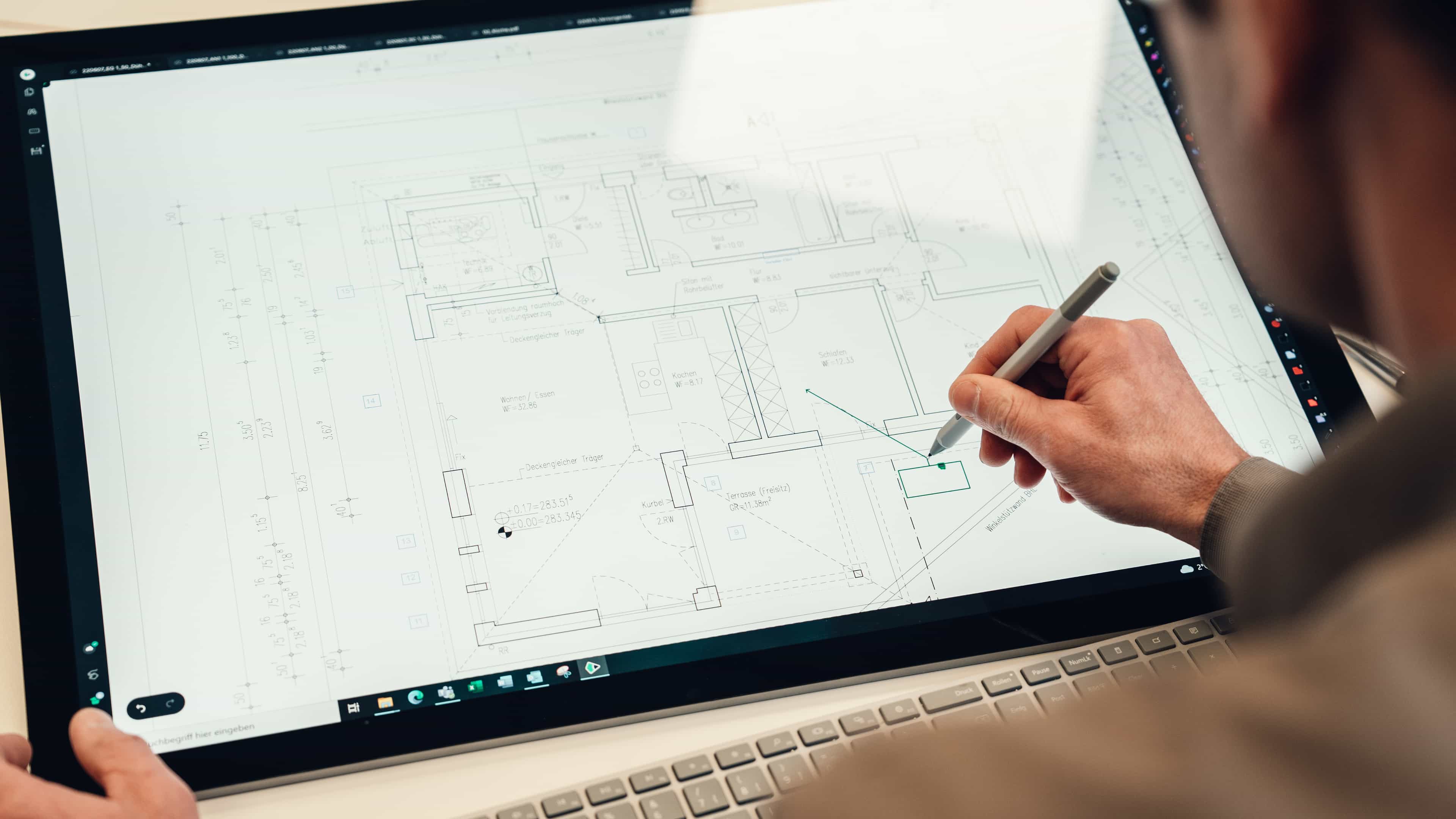 Person arbeitet mit einem Stylus an technischer Zeichnung auf einem großen Bildschirm.