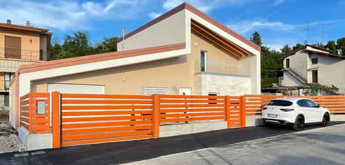 Einfamilienhaus in Erba mit Pultdach, Garage und orangefarbenem Zaun, Außenansicht Hausbausatz Haas Holzbausysteme