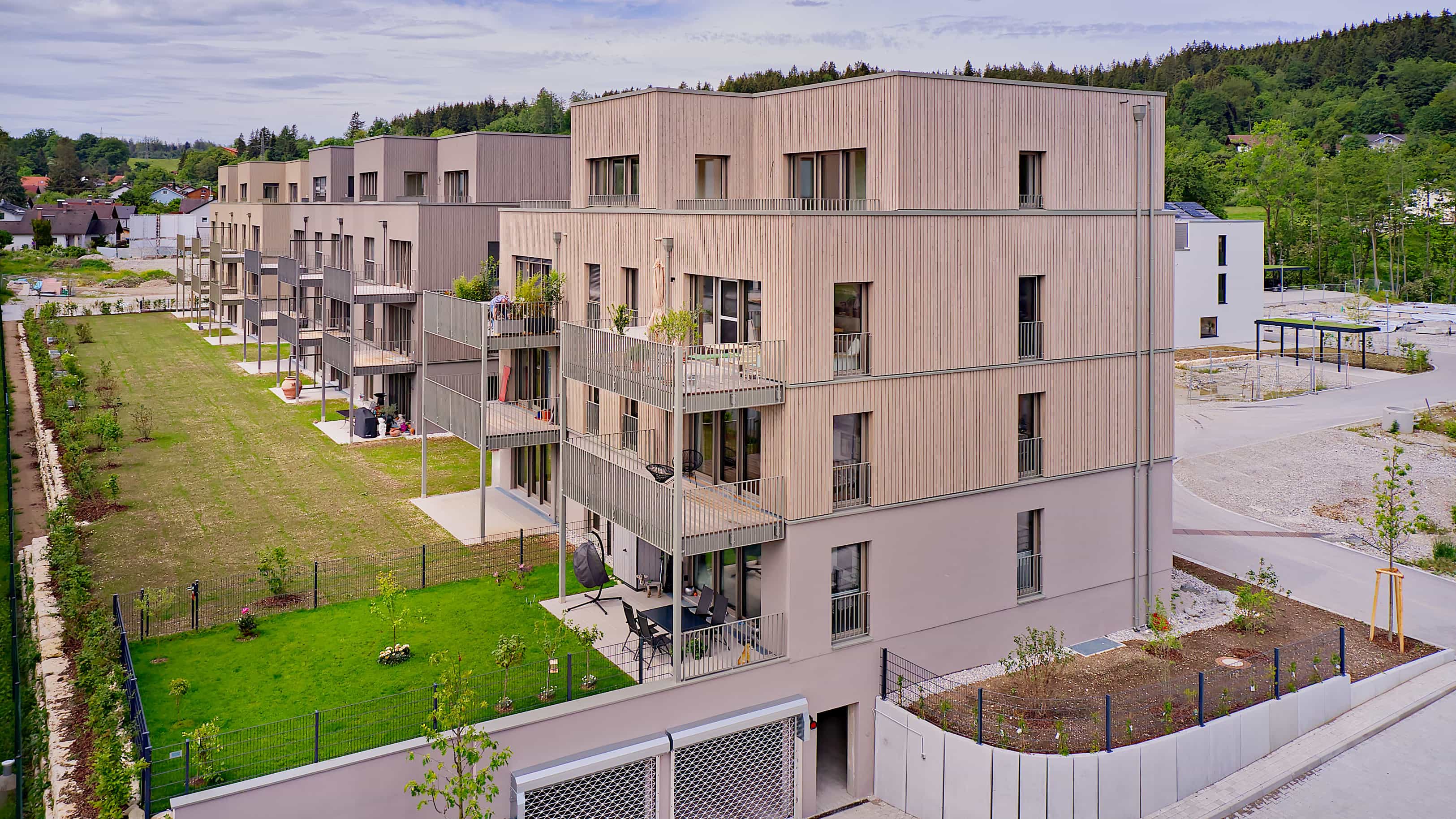 Luftaufnahme der drei Mehrfamilienhäuser mit Holzfassade und Mietergärten im Wohnquartier im Pfaffenwinkel